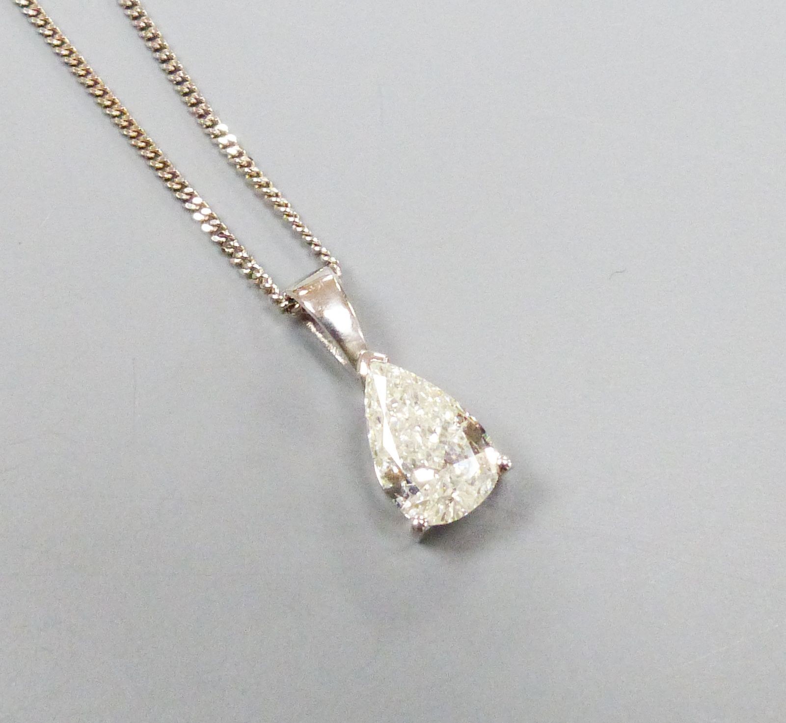 A modern white metal and solitaire pear shaped diamond set pendant, overall 14mm, on and 18ct white gold fine link chain, 40cm, gross weight 2.9 grams